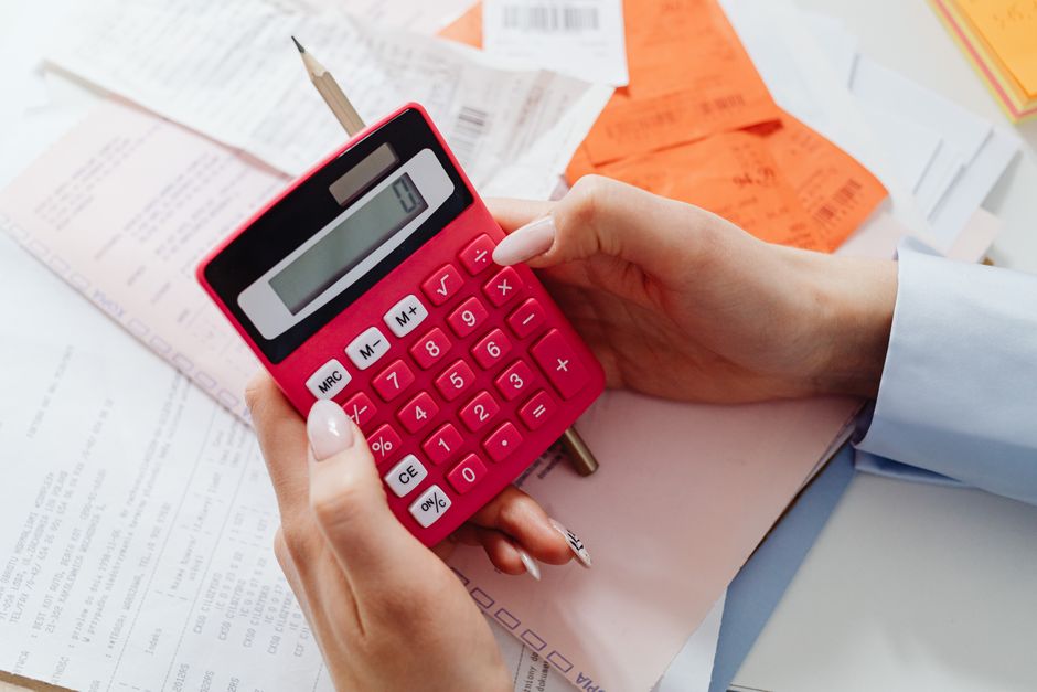 Close-up of hands holding a calculator while managing finances with documents